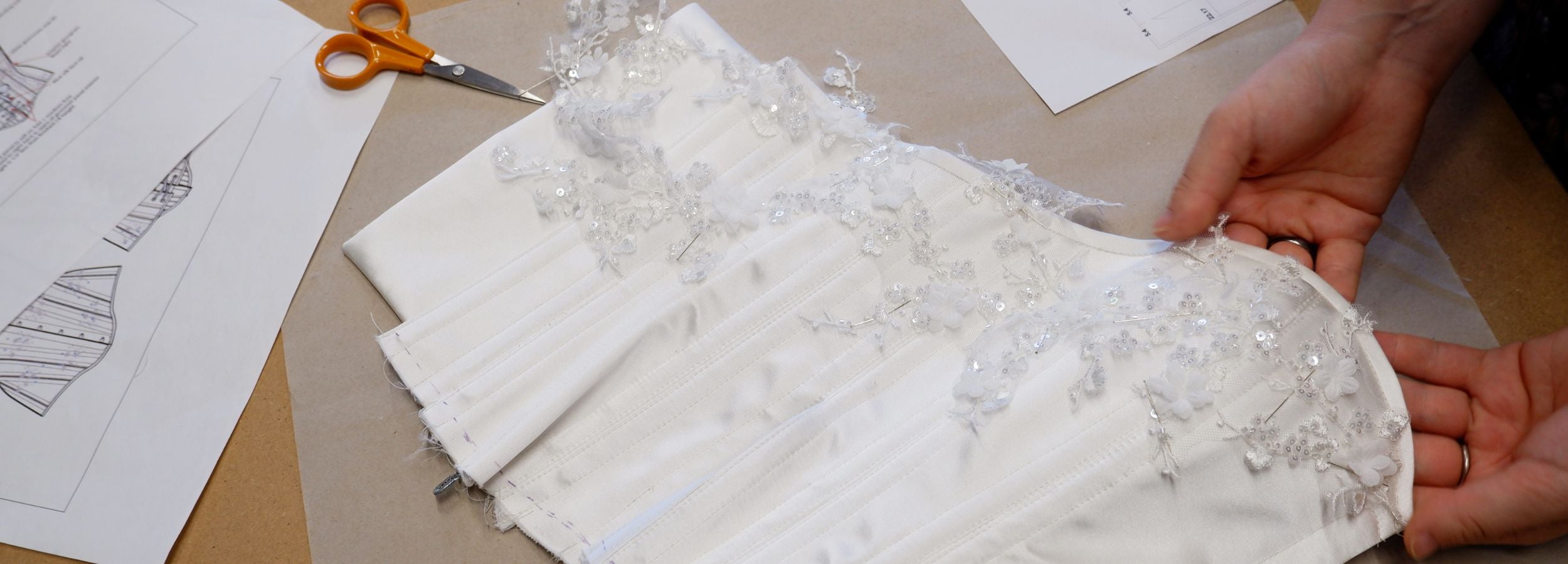 Person working with fabric on a table with patterns and scissors