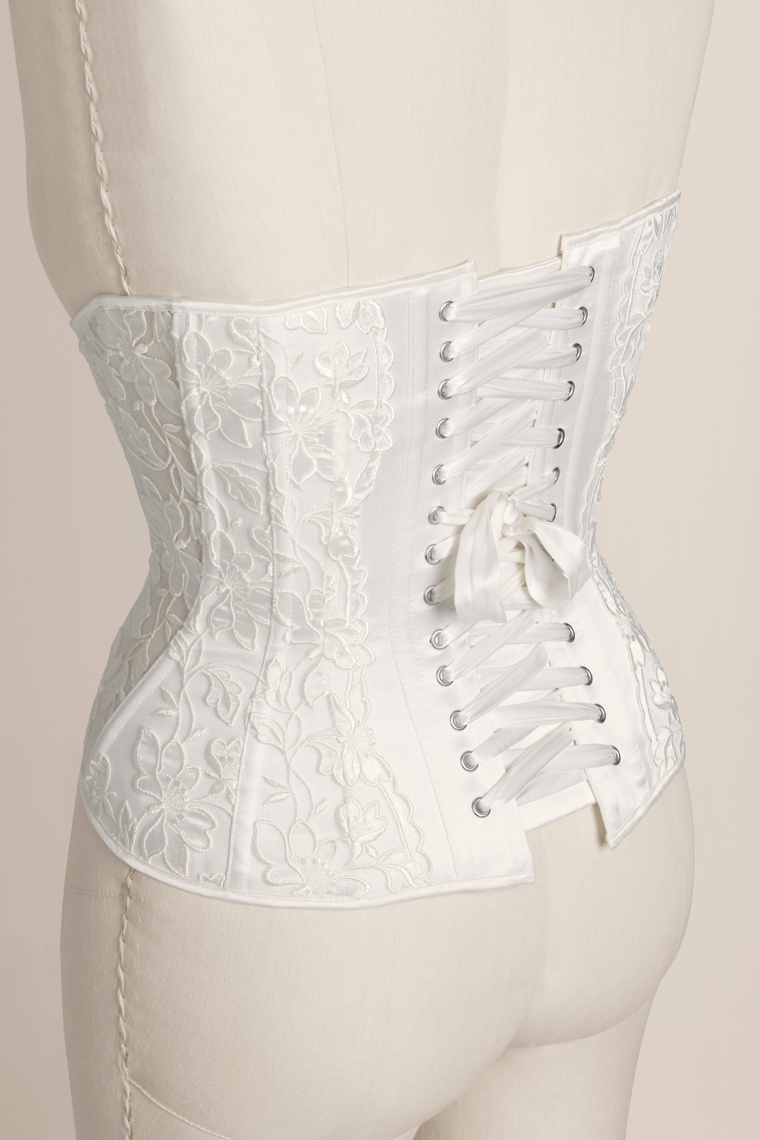 White lace corset on a mannequin against a neutral background