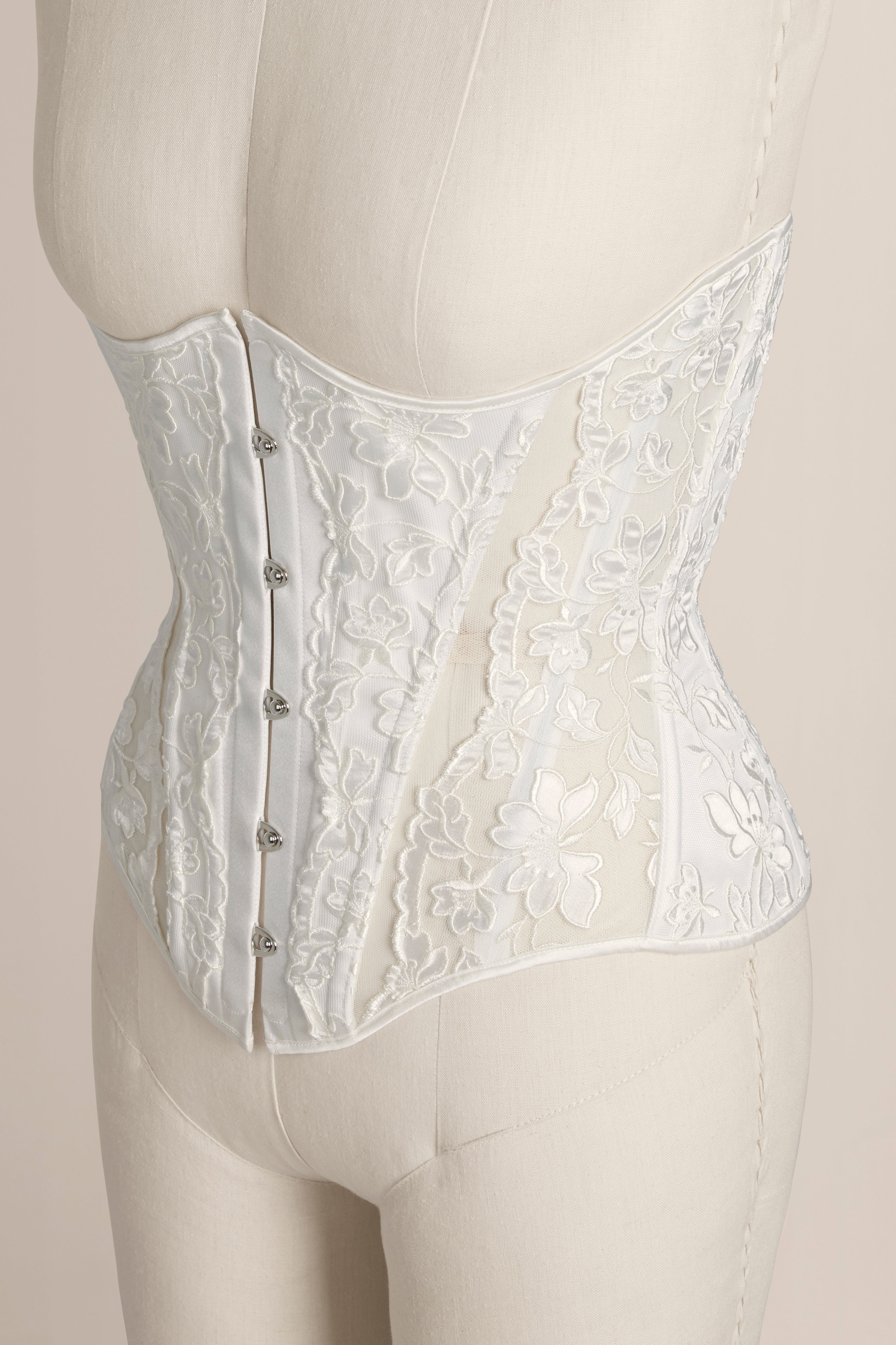 White lace corset on a mannequin against a plain background