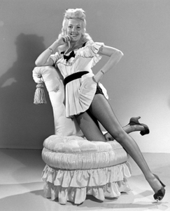 Vintage picture of Betty Grable in a dress and stockings, kneeling on a chair