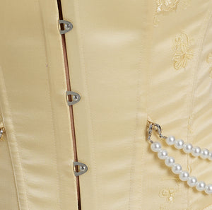 Close-up of yellow corset busk closure and pearl detailing 