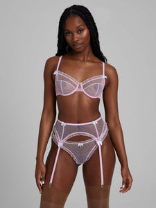 Woman wearing bubble-gum pink lace lingerie set with bra, thong and suspenders