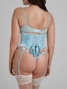 Women wearing blue lace bra and thong with white bows, and waspie with suspender straps from behind